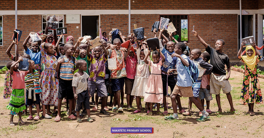 Kinderen in Malawi zitten op de grond omringd door maïskolven en kijken naar de camera