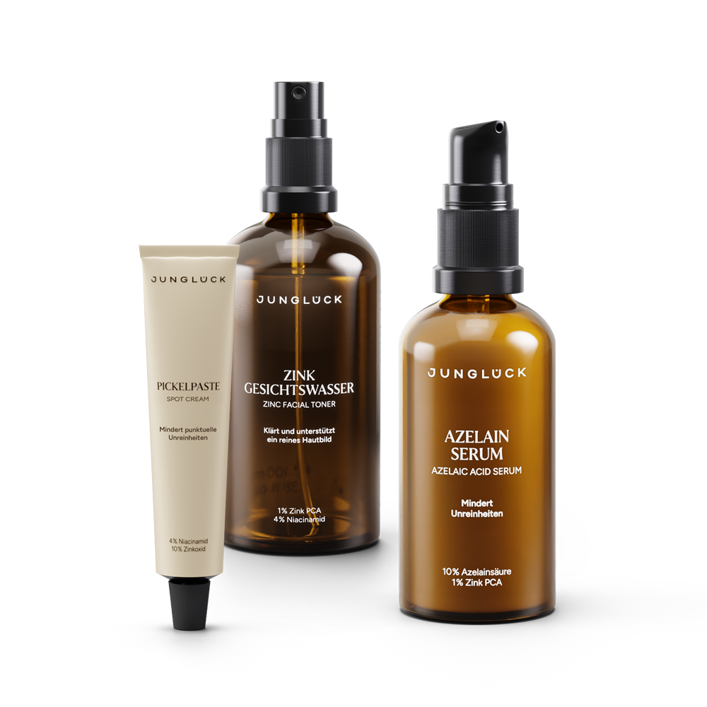 Three JUNGLÜCK skincare products in amber glass bottles, arranged against a black background.