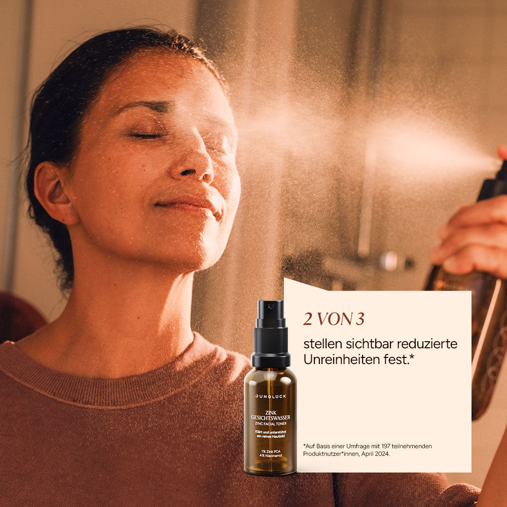 Een vrouw spuit ‘ Zink Gezichtstoner ’ op haar gezicht. Op de voorgrond staat een bruine glazen fles. De achtergrond is in zachte tinten.