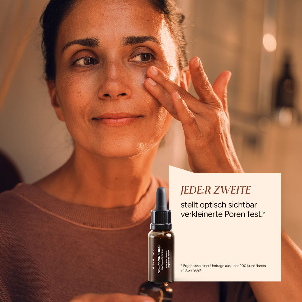 Een vrouw brengt ‘ Niacinamide Serum ’ aan op haar gezicht; op de achtergrond is het bruine glazen flesje te zien.