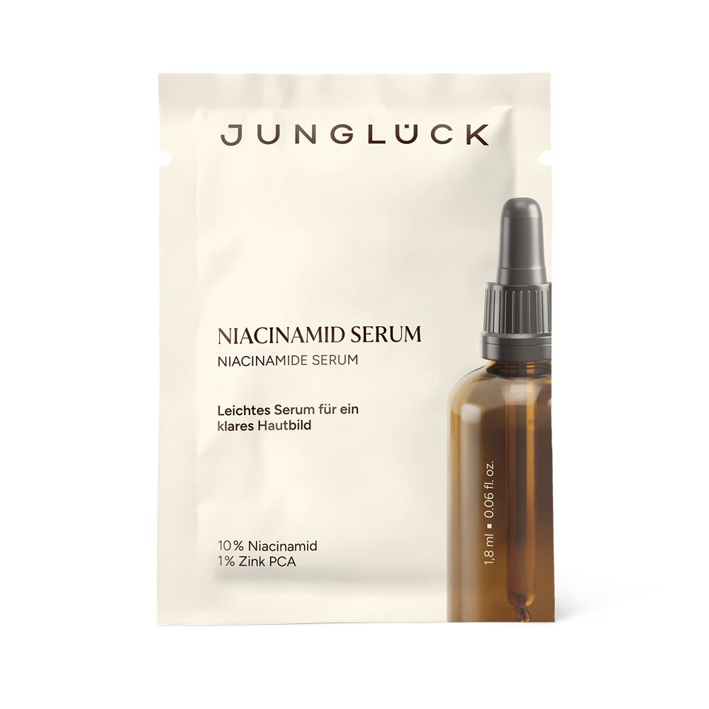 Una bustina beige con l'etichetta «Jungluck Niacinamide Sieri a un flacone con contagocce color ambra e tappo scuro.