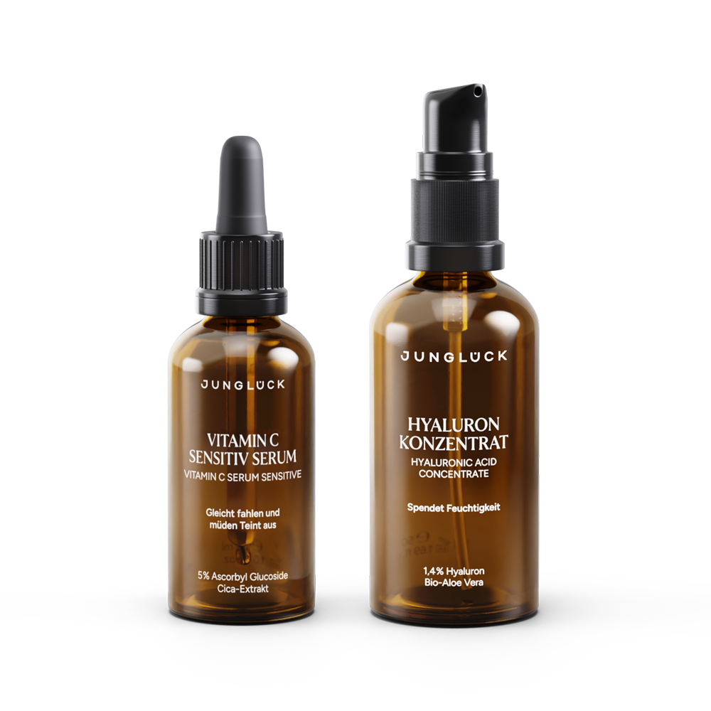 Zwei Braunglasflaschen von JUNGLÜCK, ein Serum und ein Hyaluronkonzentrat, stilvoll präsentiert.